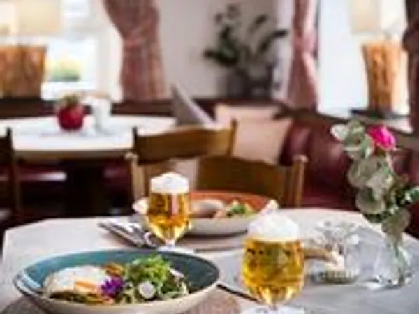 Gedeckter Tisch in der Bierstube mit frisch gezapftem Bier, Salatteller und einer Rose