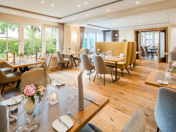 Eingedeckte Tische im Restaurant mit hellem Holzboden und Blick ins Grüne