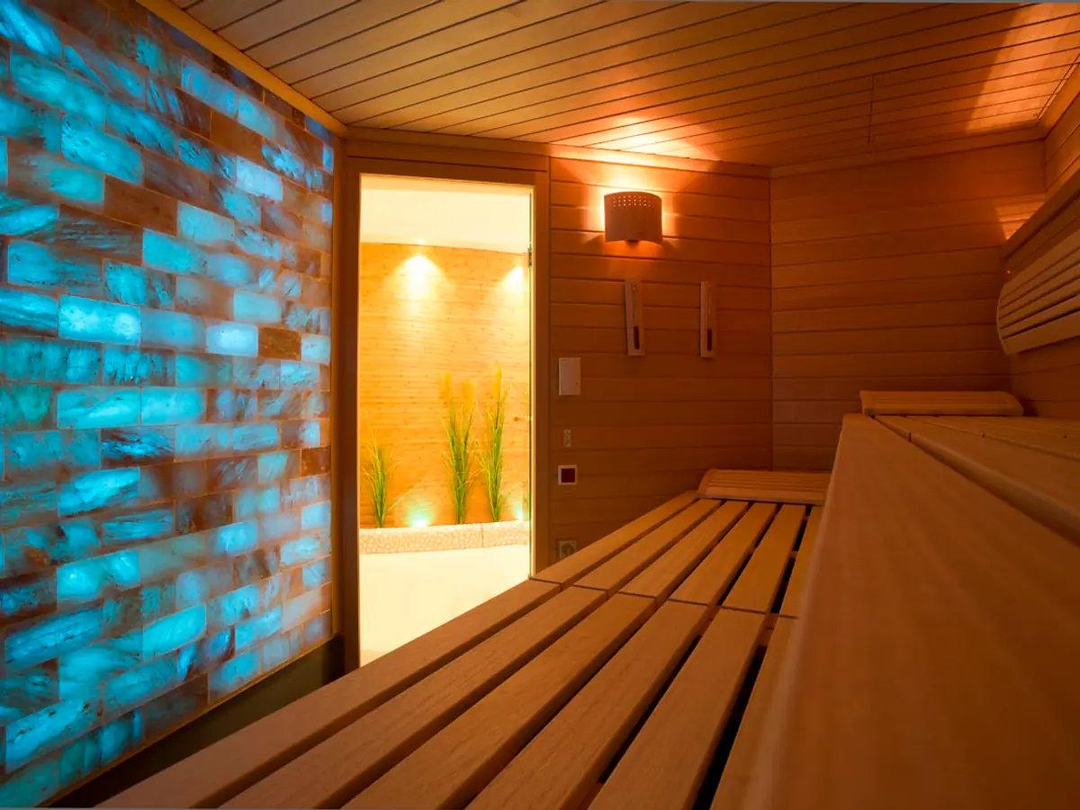 Bio-Sauna mit Holzbänken und beleuchteter Steinwand