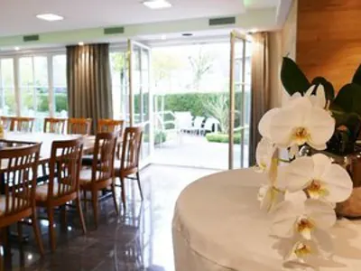 Geöffnete Flügeltür zur Terrasse, davor ein Stehtisch mit weißer Husse und Orchidee
