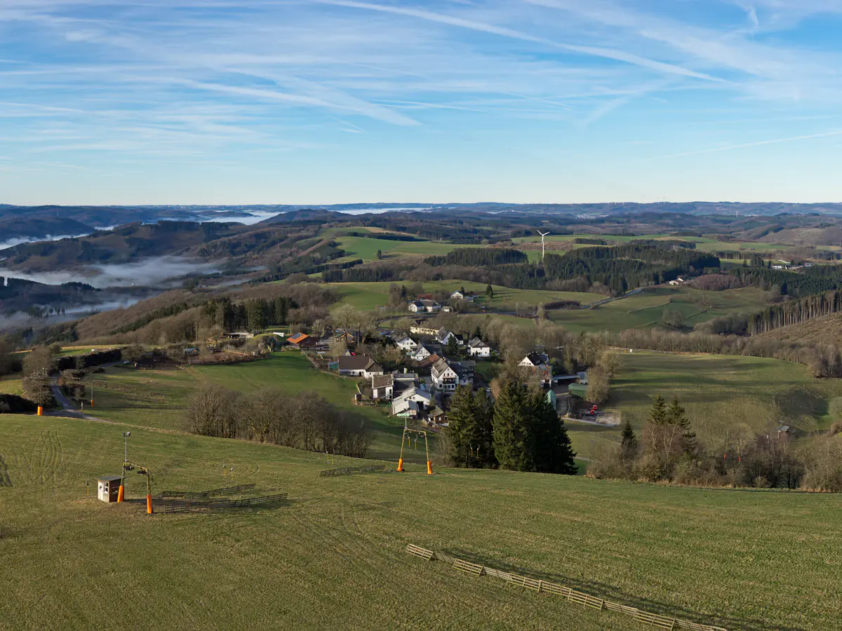 Blick über die Hänge von Wildewiese mit Liftanlage und dem Ort im Hintergrund
